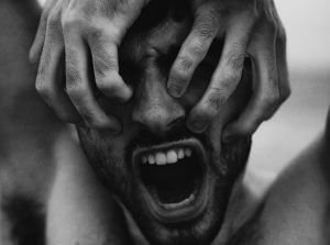 grayscale photo of person with mouth open and hands covering eyes
