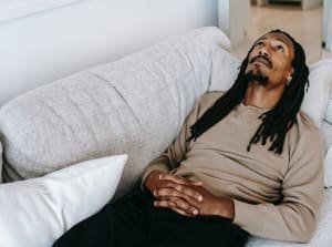 person laying on sofa looking up with hands crossed over abdomen