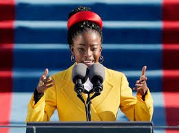 person giving speech wearing yellow blazer and red headband