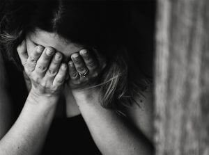 person with head down and eyes covered by hands