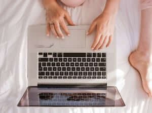 ariel view of person in sitting on bed with laptop