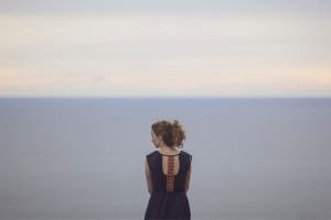 person standing alone facing the horizon in background