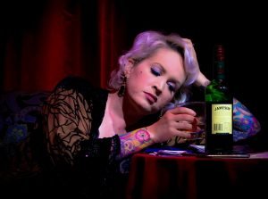 person sitting alone at a table with a bottle of liquor